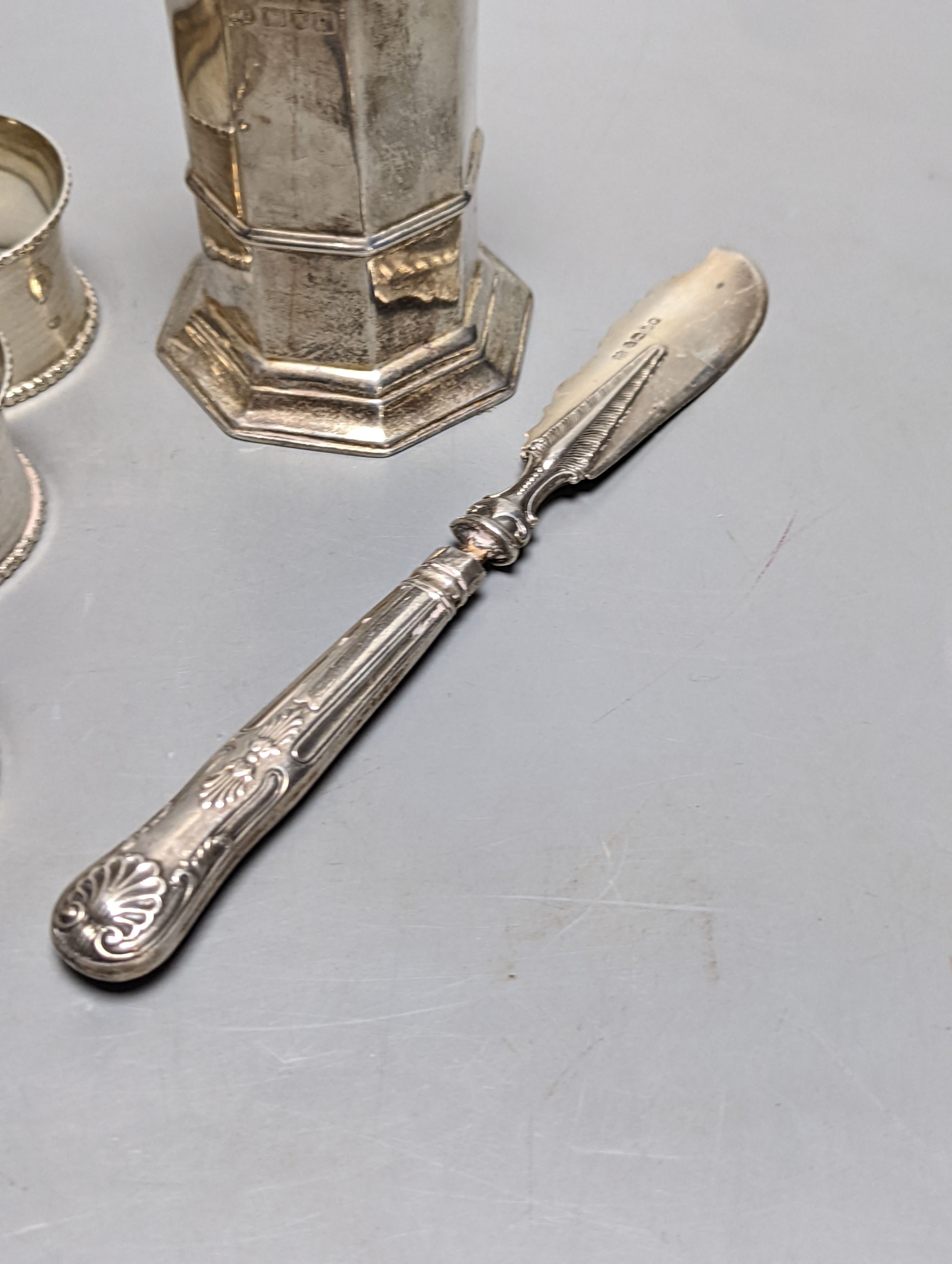 A set of six George V silver napkin rings, Birmingham, 1915, a silver sugar caster and silver butter knife.